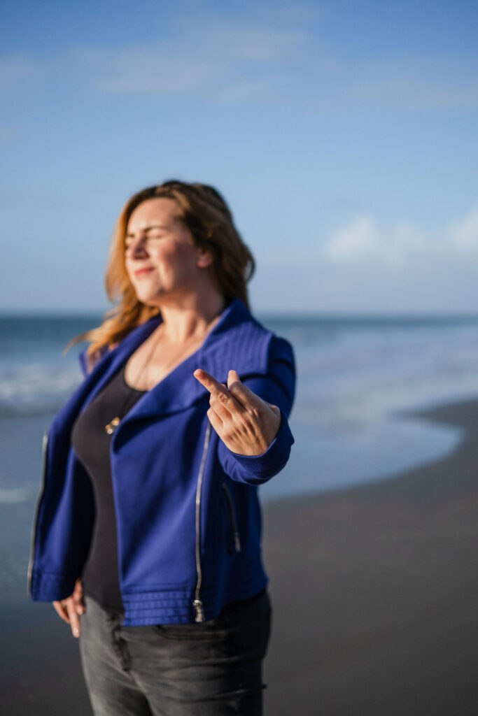 Woman on the beach holding up a middle finger.